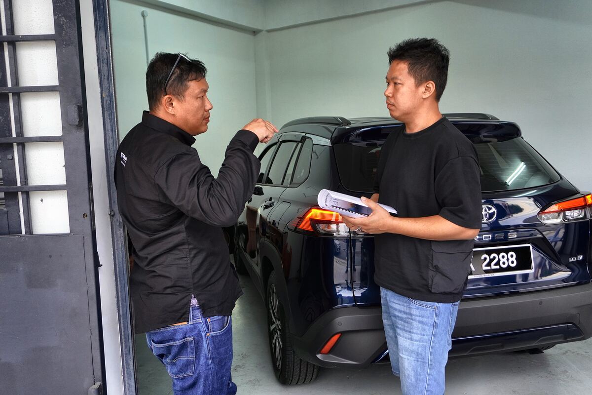 Trainer and attendee discussing a vehicle installation outside a demo car.